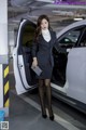 A woman in a business suit standing next to a car.