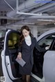 A woman in a business suit standing next to a car.