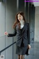 A woman in a black and white striped suit leaning against a wall.