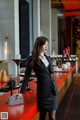 A woman in a black and white striped suit standing at a bar.