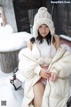 A woman sitting on a bench in the snow wearing a hat.