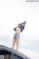 A woman standing on top of a car with her arms outstretched.