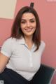 A woman sitting on a chair in front of a pink wall.