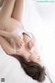 A woman laying on top of a white bed.