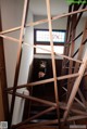 A woman standing in front of a wooden staircase.