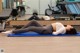 A woman laying on a blue mat in a gym.