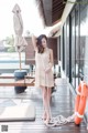 A woman in a white dress standing on a wooden deck.