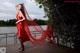 A woman in a red dress standing on a bridge.