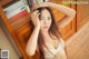 A woman in a white lingerie leaning against a bookshelf.