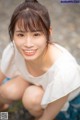 A woman in a white shirt and blue skirt posing for a picture.