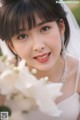 A woman in a wedding dress holding a bouquet of flowers.