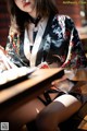 A woman in a kimono sitting at a table with chopsticks.