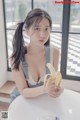 A woman sitting at a table holding a banana.