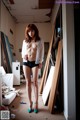 A naked woman standing in a room next to a bed.