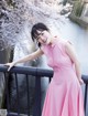 A woman in a pink dress standing on a bridge.