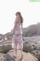 A woman standing on a rock on the beach.