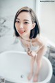 A woman sitting in a bathtub smiling at the camera.