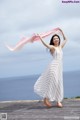 A woman in a white dress holding a pink scarf.