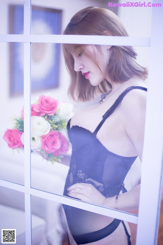 A woman in a black lingerie holding a bouquet of flowers.