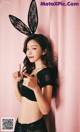 A woman in a black lingerie with bunny ears on her head.