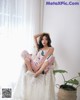 A woman sitting on top of a white chair next to a plant.