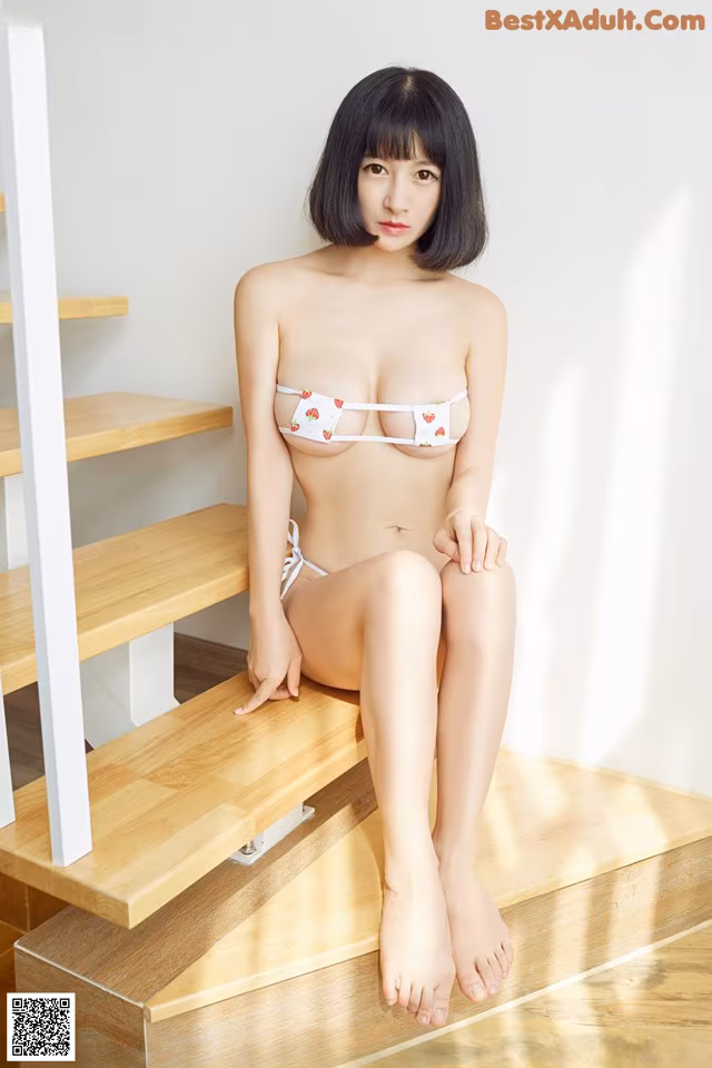 A woman in a white bikini sitting on a wooden staircase.