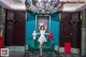 A woman in a white dress standing in front of a chandelier.