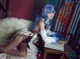 A woman with blue hair sitting on a bed.