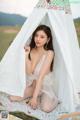 A woman in a white lingerie sitting in a tent.