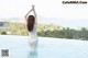 A woman in a white dress standing in a swimming pool.