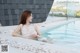 A woman in a white dress sitting in a pool.