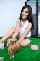 A woman sitting on the floor petting a small dog.