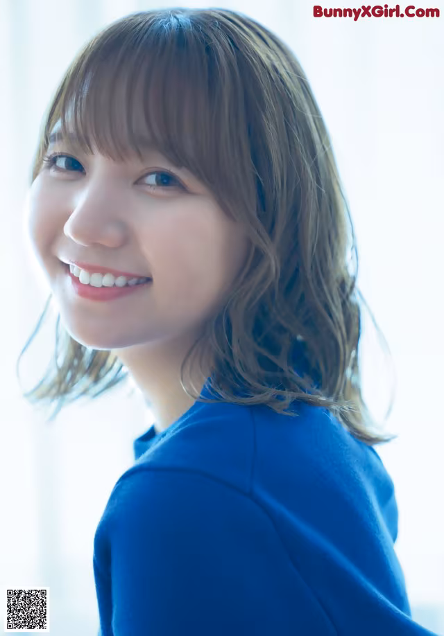 A woman in a blue sweater smiles at the camera.