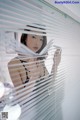 A woman standing in front of a window with blinds.