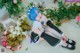 A woman with blue hair sitting on the floor next to flowers.