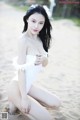 A woman in a white bathing suit sitting on a beach.