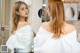 A woman standing in front of a mirror in a bathroom.