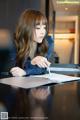 A woman sitting at a table writing on a piece of paper.