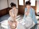 A couple of women sitting on top of a wooden floor.