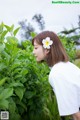 A woman with a flower in her hair standing in a field.