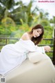 A woman in a white dress sitting on a white couch.