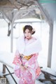 A woman in a pink kimono standing in the snow.