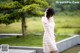 A woman in a white dress standing next to a pond.