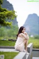 A woman in a pink dress sitting on a stone ledge.