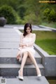 A woman in a white dress sitting on some steps.