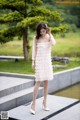 A woman in a white dress is standing on some steps.