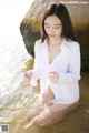 A woman in a white shirt is sitting in the water.