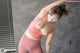 A woman in a pink sports bra top and pink leggings with a mask on.