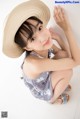 A young woman wearing a straw hat sitting on the floor.