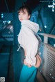 A woman in a white hoodie and blue leggings posing for a picture.